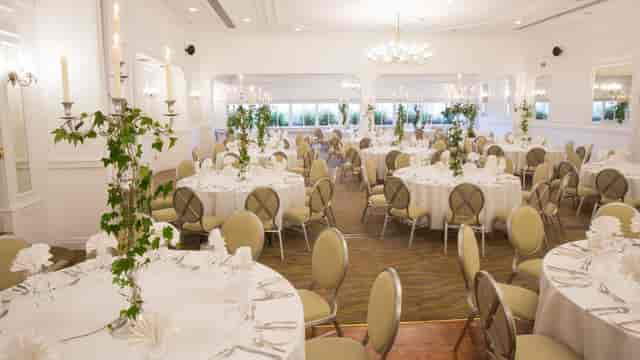 Ballroom setup with white tables and candelabras, ideal for formal galas or corporate banquets.