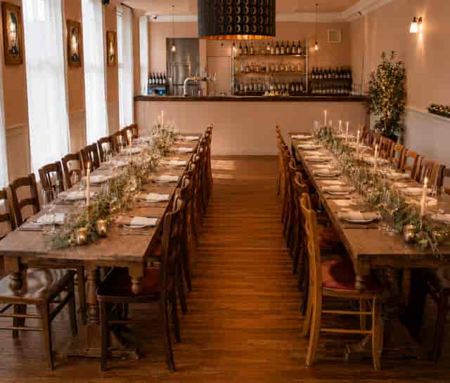 Rustic wedding reception with twin long tables, greenery runners, and wood decor at The Bull.
