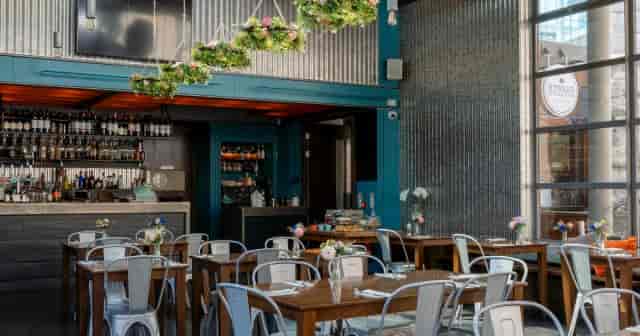 Industrial-chic dining room with floral decor for corporate mixers and networking events.
