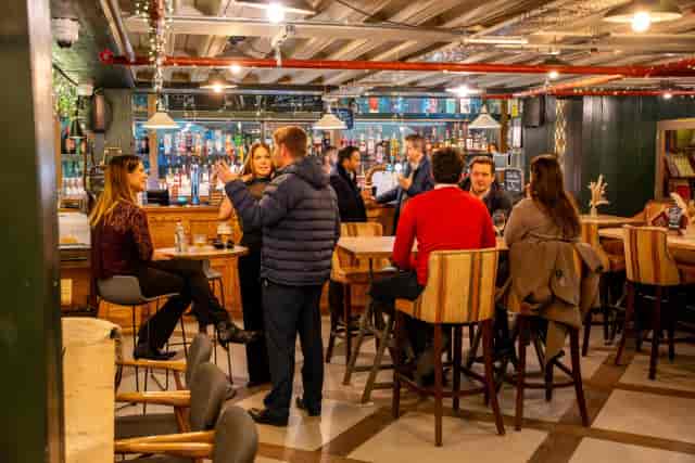 Modern bar venue for corporate networking mixer with flexible high-top seating.