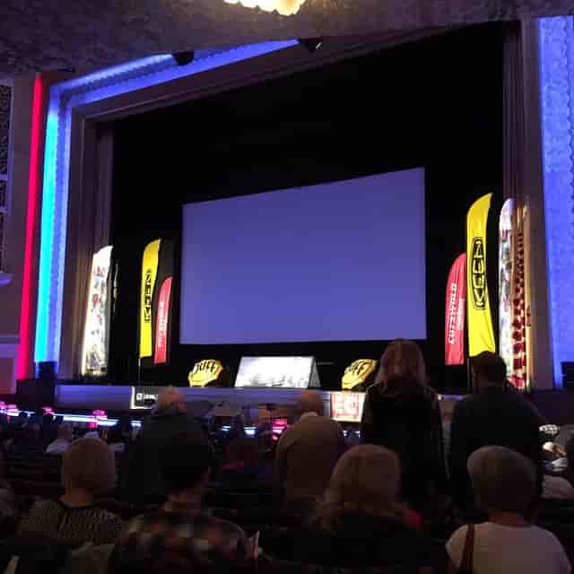 Corporate stage setup with projection screen in Audenshaw School theatre for business event.