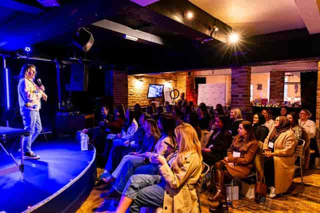 Speaker on stage at CFC Studio Main Hall, rustic brick venue for corporate workshops.
