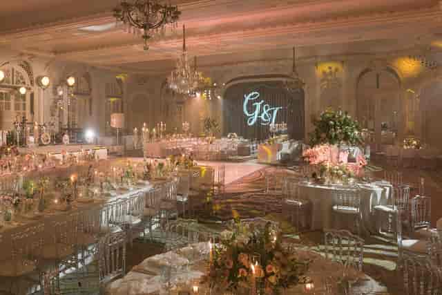 Modern luxury ballroom event venue with banquet tables and artistic gobo lighting.