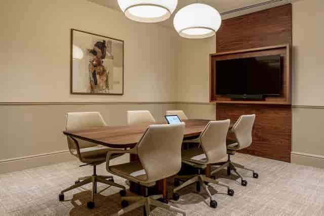 Small breakout room with walnut table for hybrid meetings and professional team collaboration.
