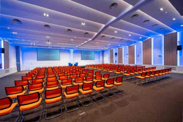 Modern Cibeles Room with orange theater seating for corporate presentations and panel discussions.