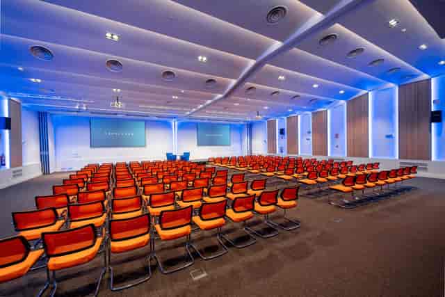 Modern theater-style conference room with blue lighting for corporate events and presentations.