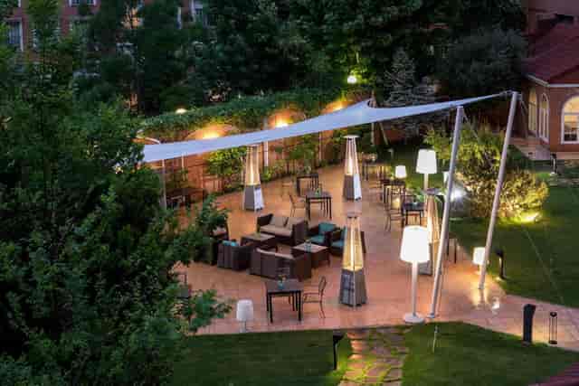 Outdoor cocktail reception at Rafaelhoteles Atocha garden with elegant tension-sail canopy.
