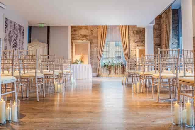 Grand Marquee wedding ceremony with pillar candles and stone walls at Ingliston Estate.