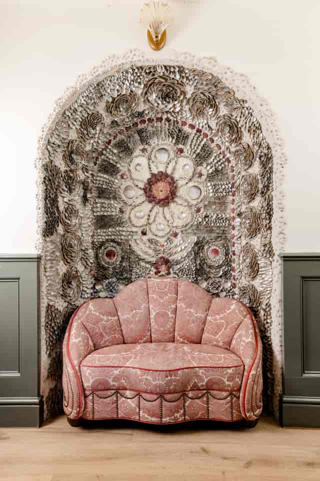 Shell-art backdrop and velvet chair at Kin House for luxury event and VIP photo venue.