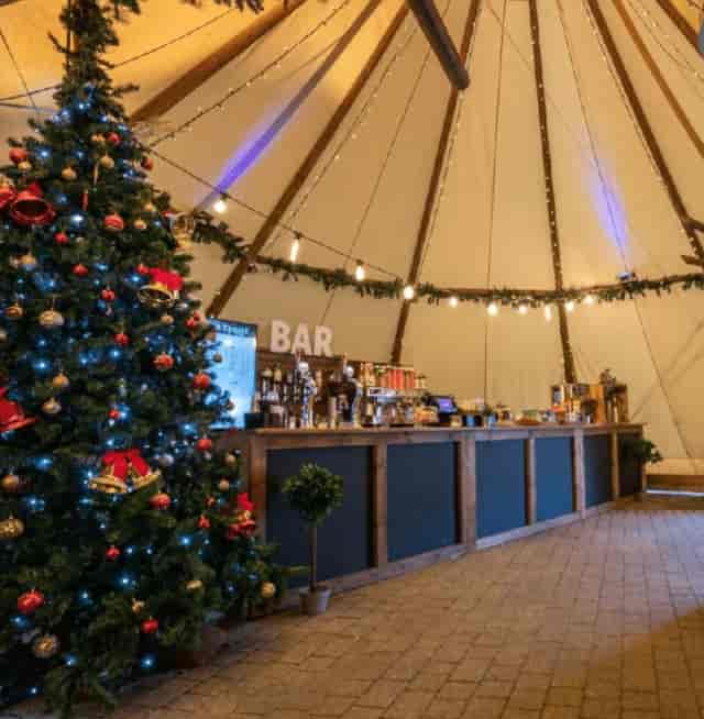 Rustic tipi bar with festive lighting for a corporate Christmas party event.