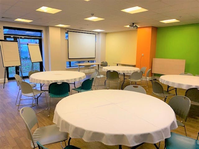 Muller Room at The LifeCentre: bright meeting space with round tables for collaboration.