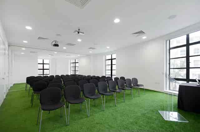 Modern conference room with green carpet, ideal for presentations and events.