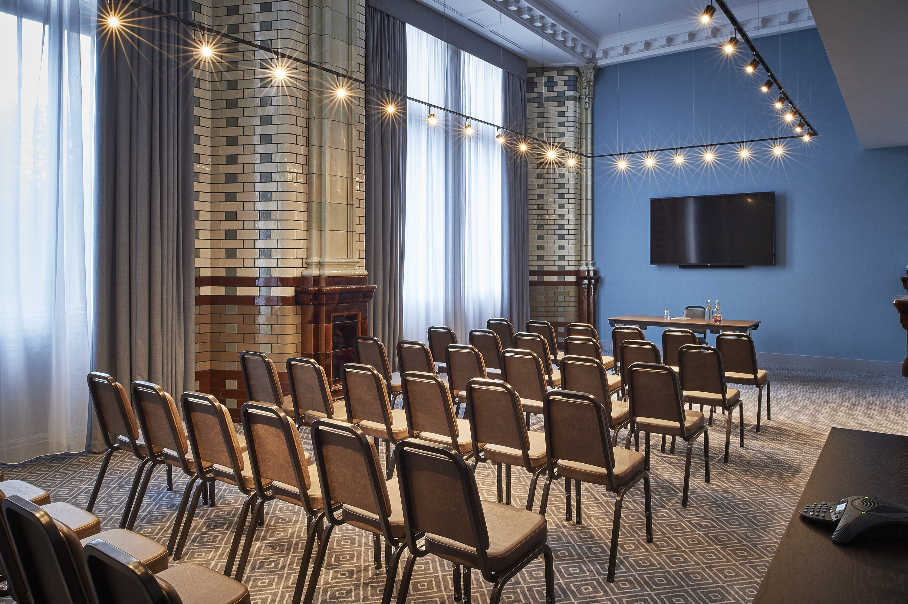 Elegant meeting space at Kimpton Clocktower Hotel with ambient lighting and presentation screen. - Banner