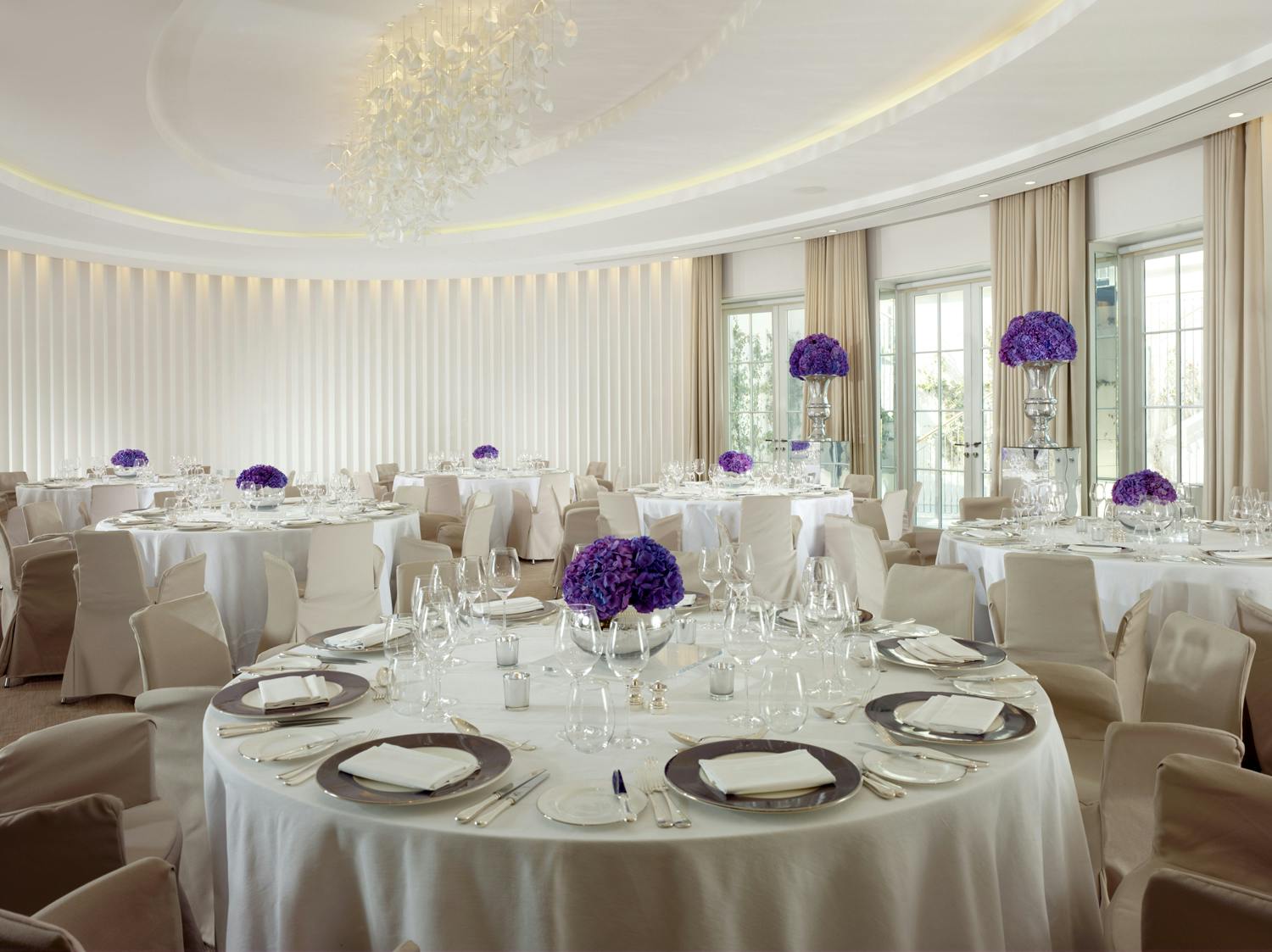 Elegant event space with round tables and purple flower centerpieces at Coworth Park.
