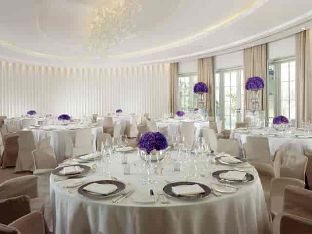 Elegant event space with round tables and purple flower centerpieces at Coworth Park.