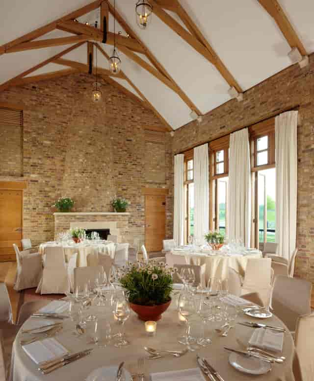 Elegant event space at The Tower House, Coworth Park with round tables and natural light.