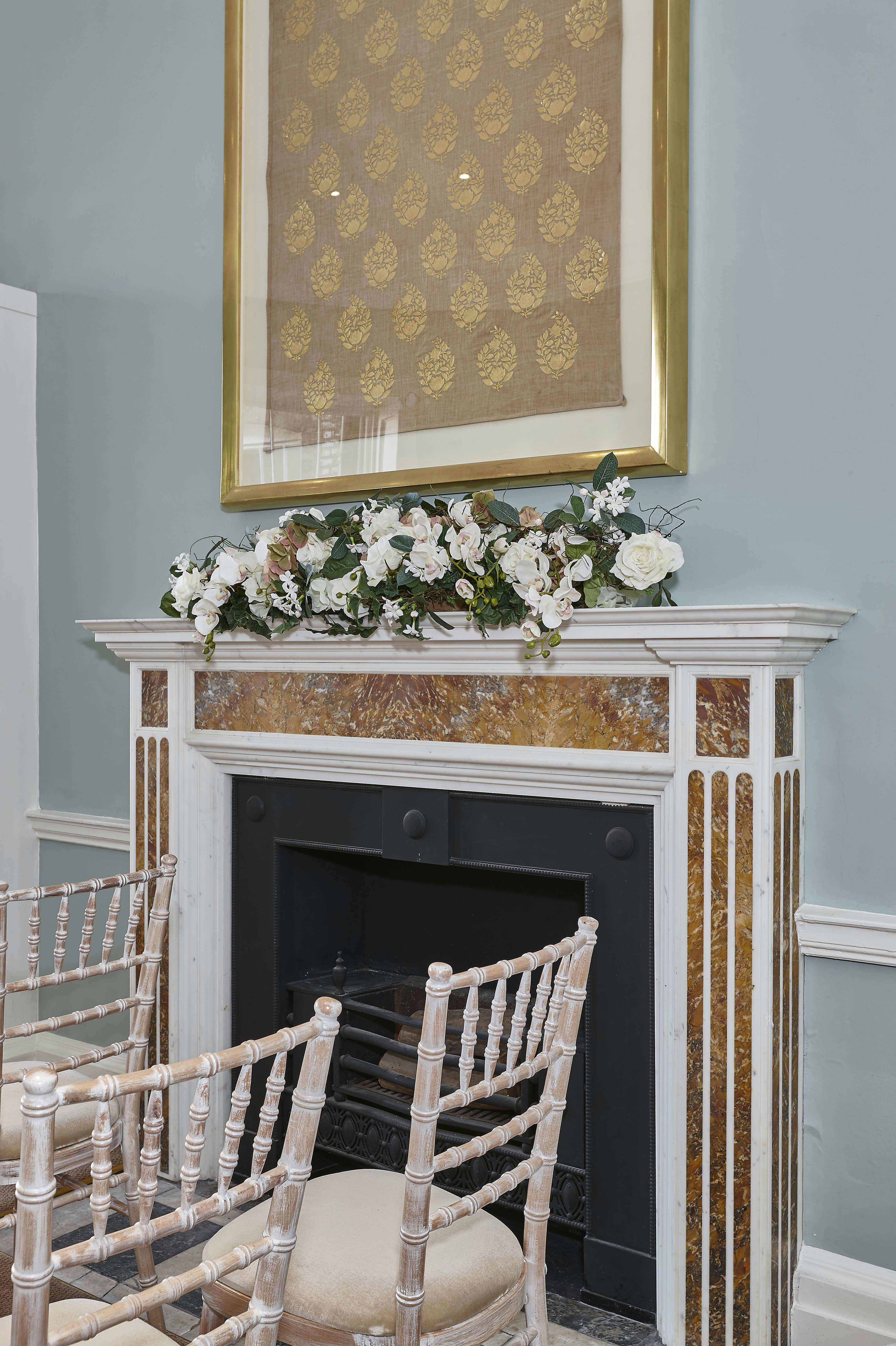 Elegant fireplace mantel with white flowers in Asia House library for events.