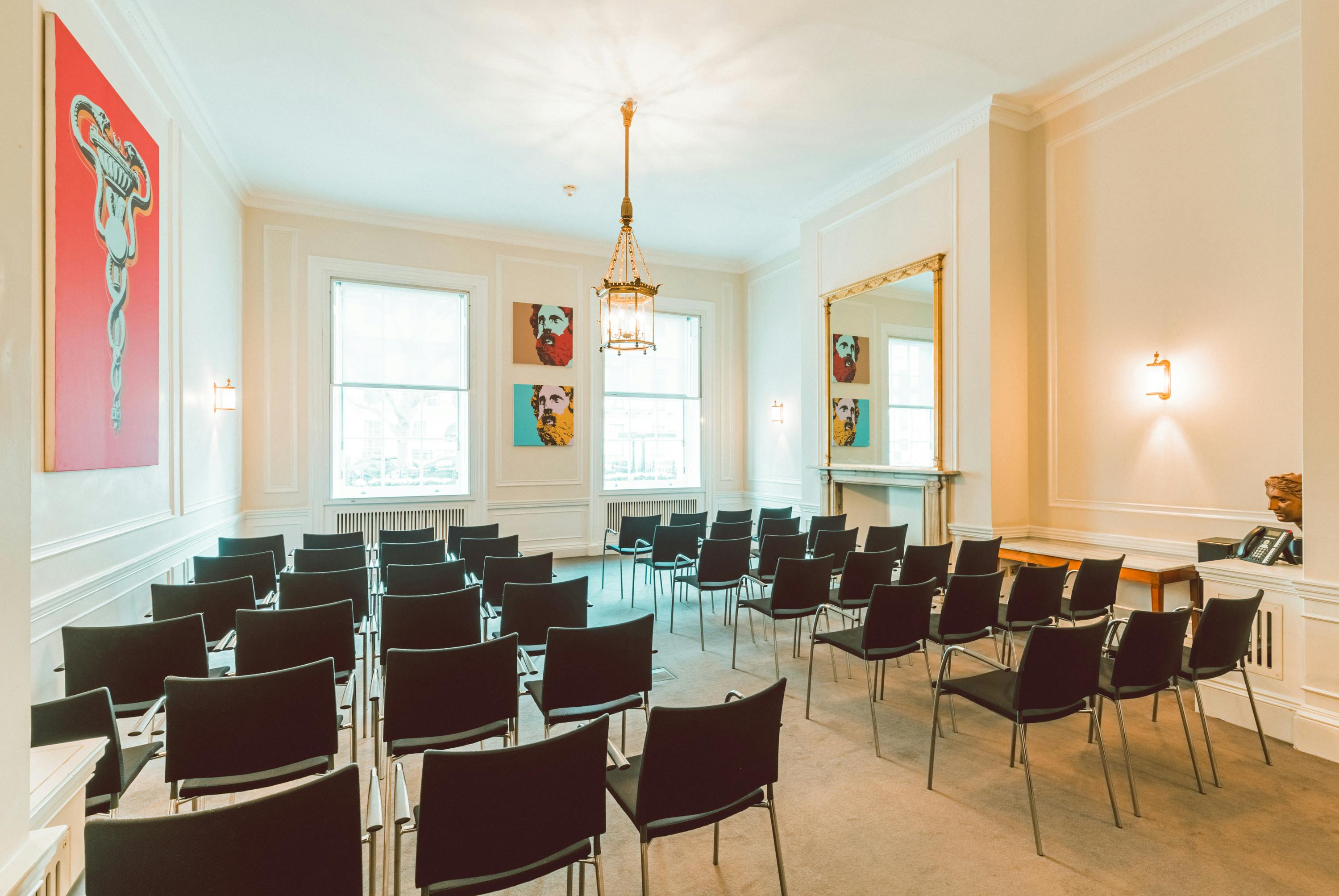 Laurie Landeau in a stylish meeting room set for workshops with black chairs and artwork.