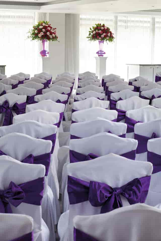 Elegant white chairs with purple sashes for weddings at Hilton London Syon Park.