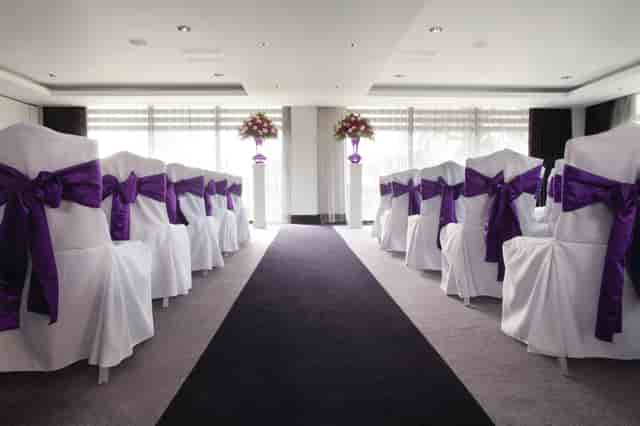 Elegant wedding venue at Hilton London Syon Park with white chairs and purple sashes.