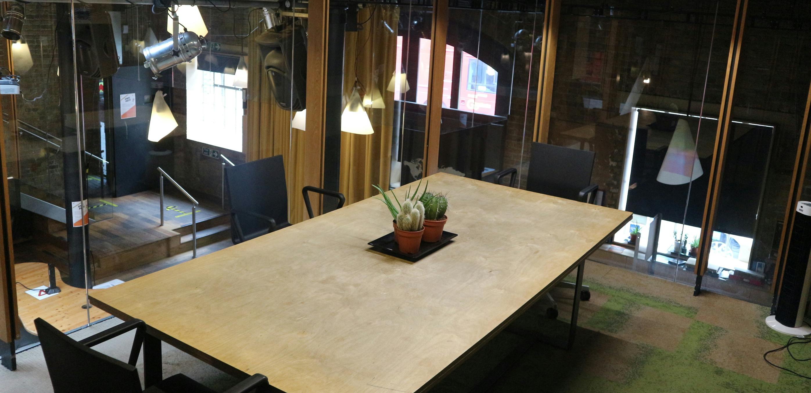 Modern meeting space with wooden table and greenery at The Glasshouse, King's Cross.