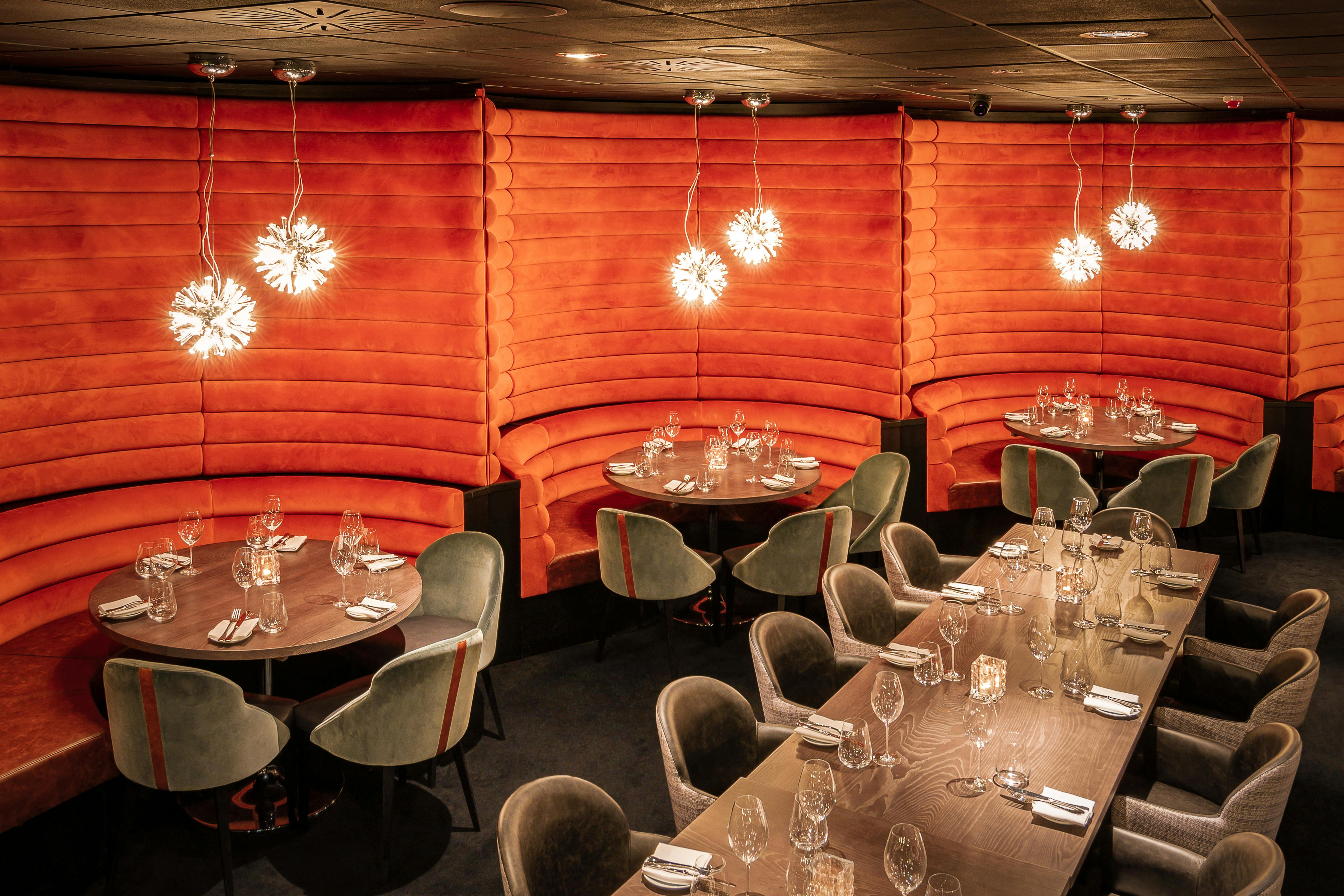 Stylish dining space at Gaucho O2 with orange walls, perfect for upscale events.