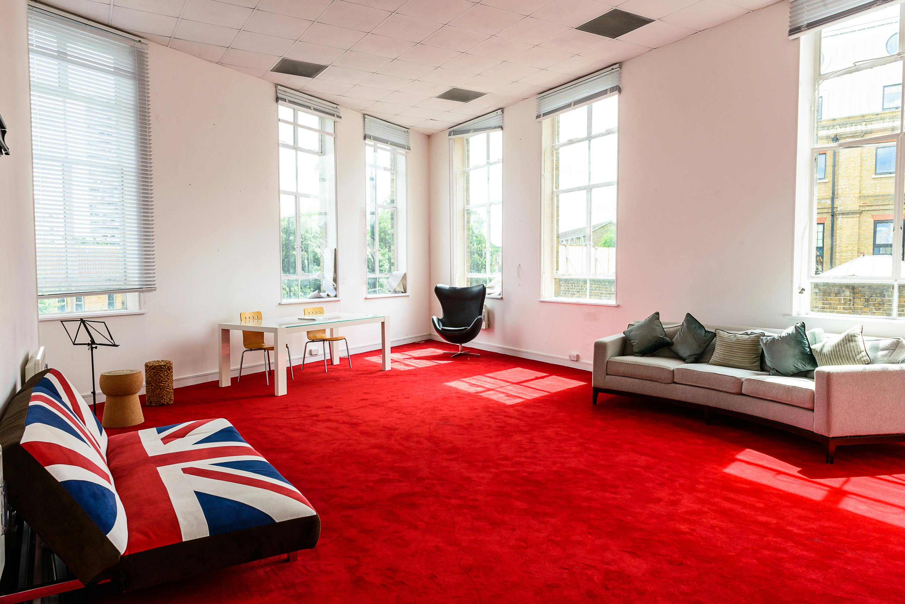 Bright meeting room with red carpet and British flag seating for creative events.