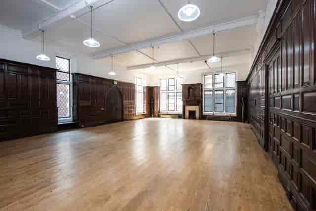 Spacious Toynbee Hall lecture room with wooden paneling, ideal for workshops and presentations.