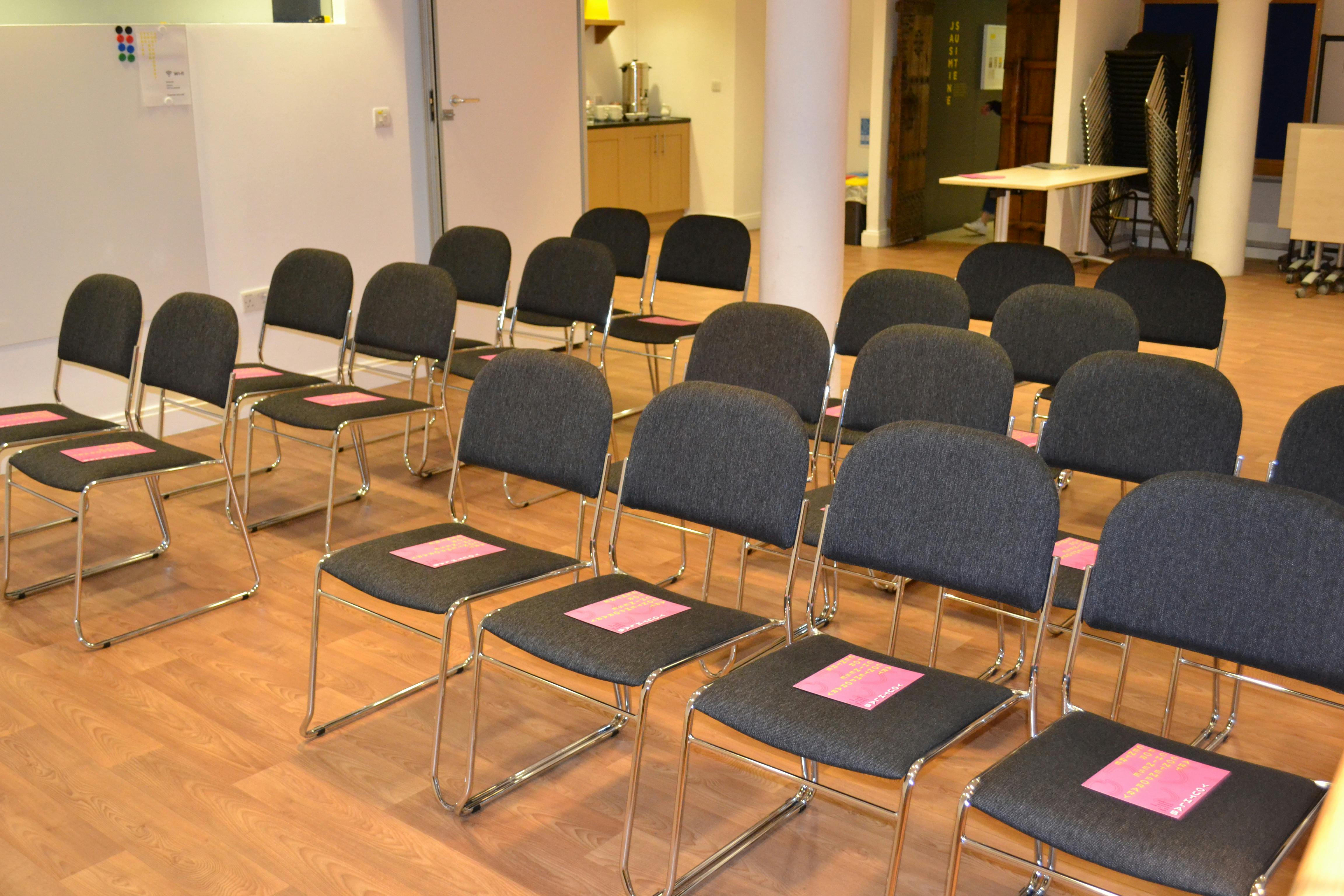 Esea Studio meeting setup with gray chairs and pink materials for engaging events.