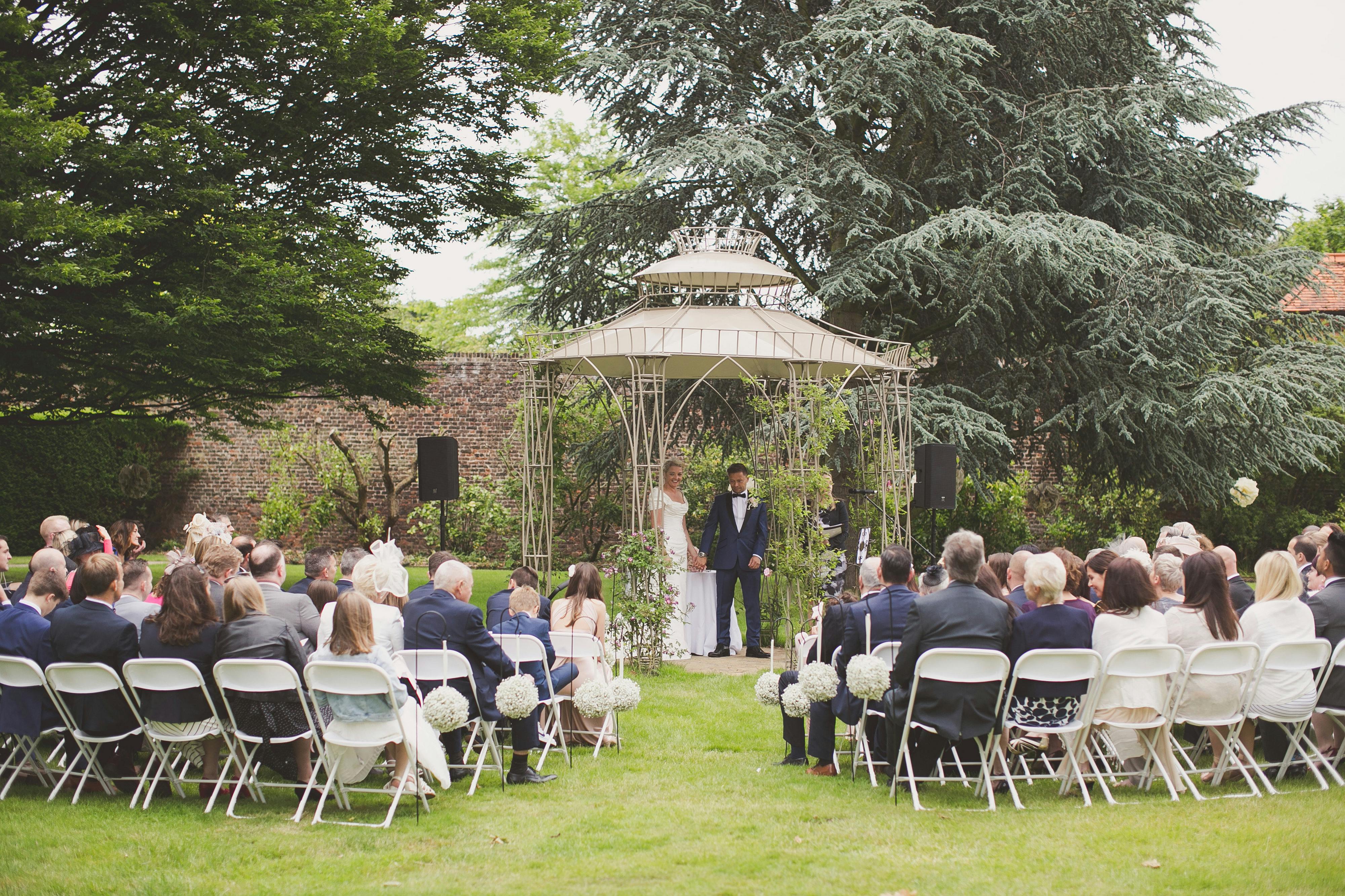 Outdoor wedding ceremony at Hampton Court Palace's Garden Room with elegant gazebo.