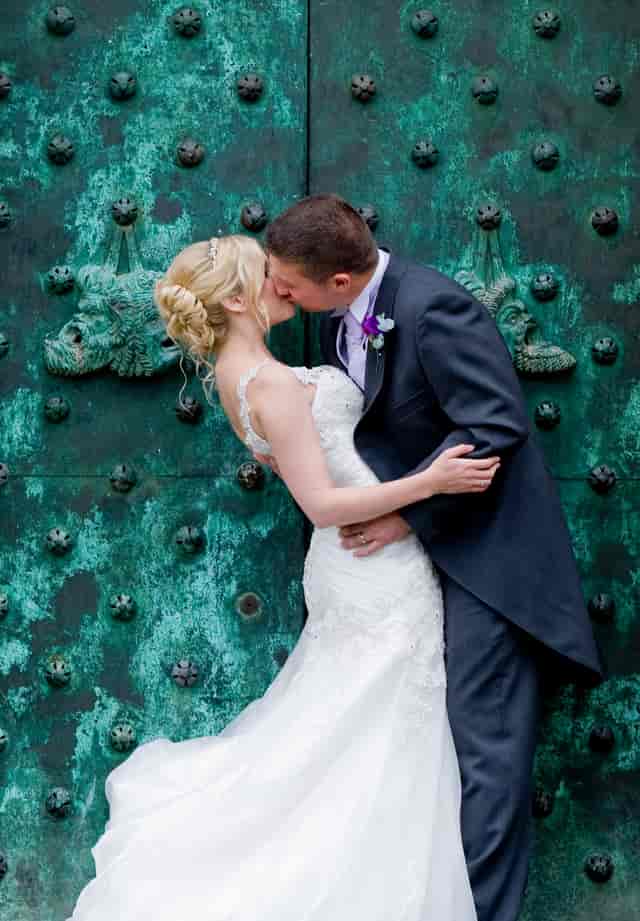 Couple kissing by ornate door at Port Lympne Hotel, perfect for wedding photography.
