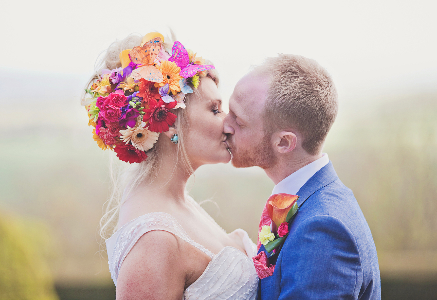 Couple kissing in vibrant floral decor at Port Lympne Hotel wedding venue.