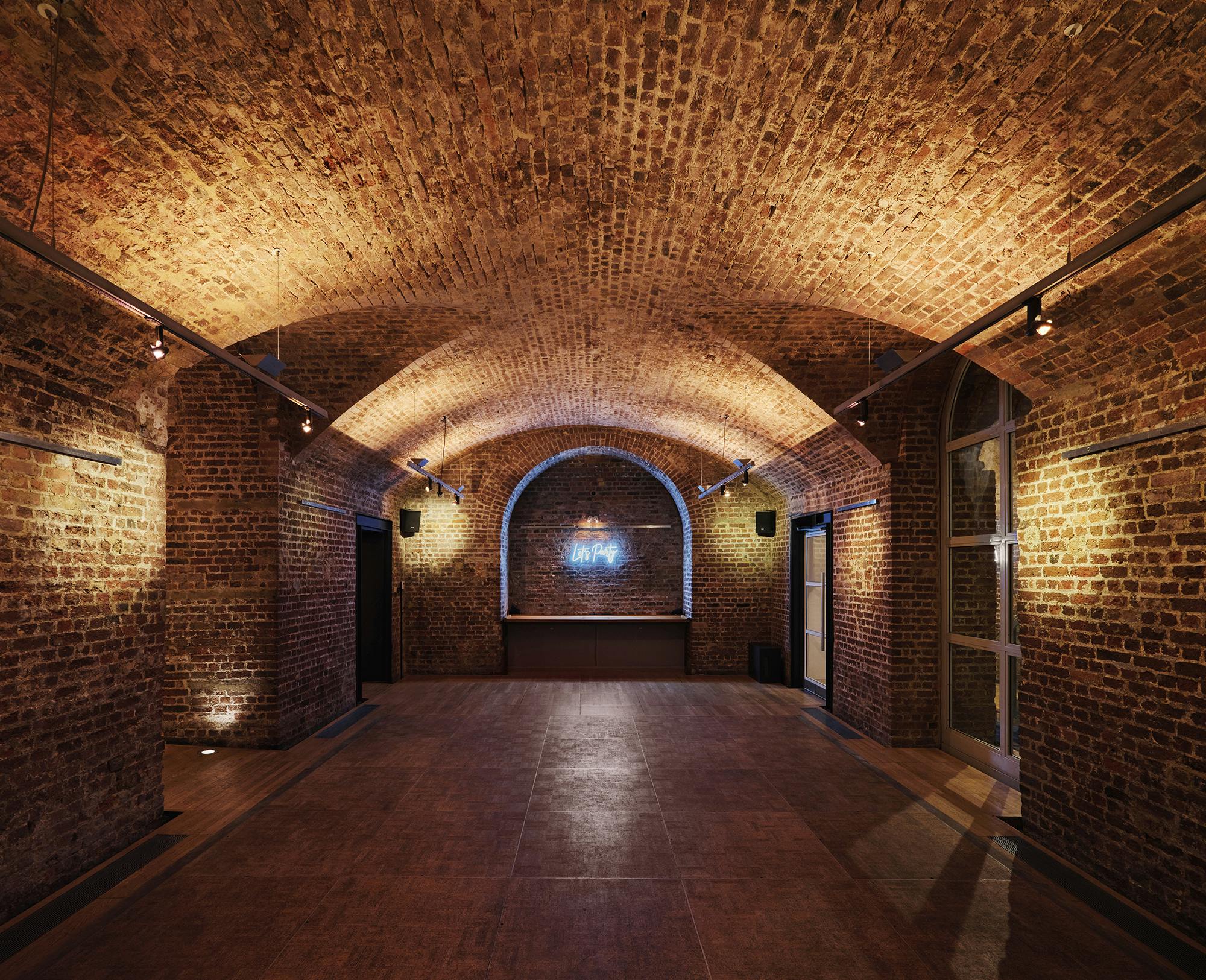 Versatile event space in RSA House with exposed brick arches, ideal for gatherings and workshops.