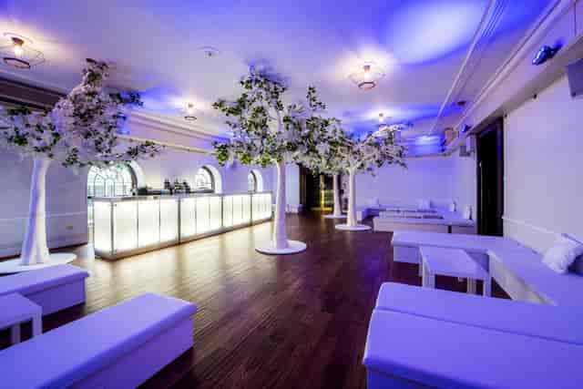 Elegant event space with white furniture and blue lighting, ideal for upscale gatherings.