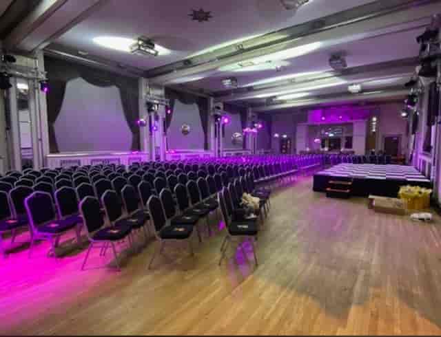 The Bloomsbury Ballroom conference setup with vibrant purple lighting and black chairs.