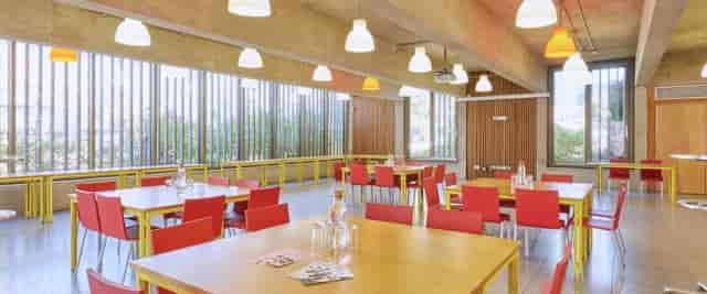 Modern dining space with red chairs at Coin Street Conference Centre for events and meetings.