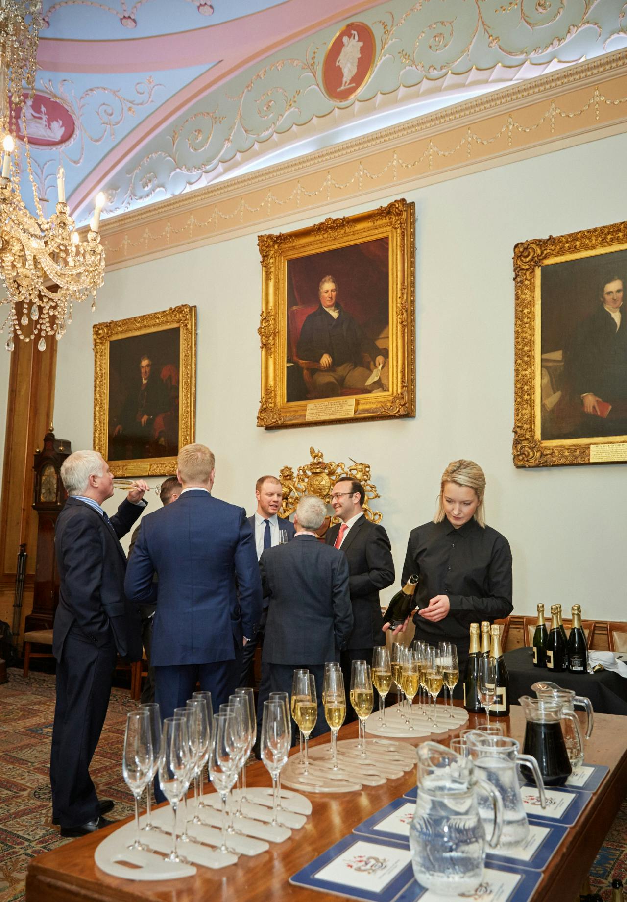 Elegant courtroom networking event with chandelier and historical portraits.