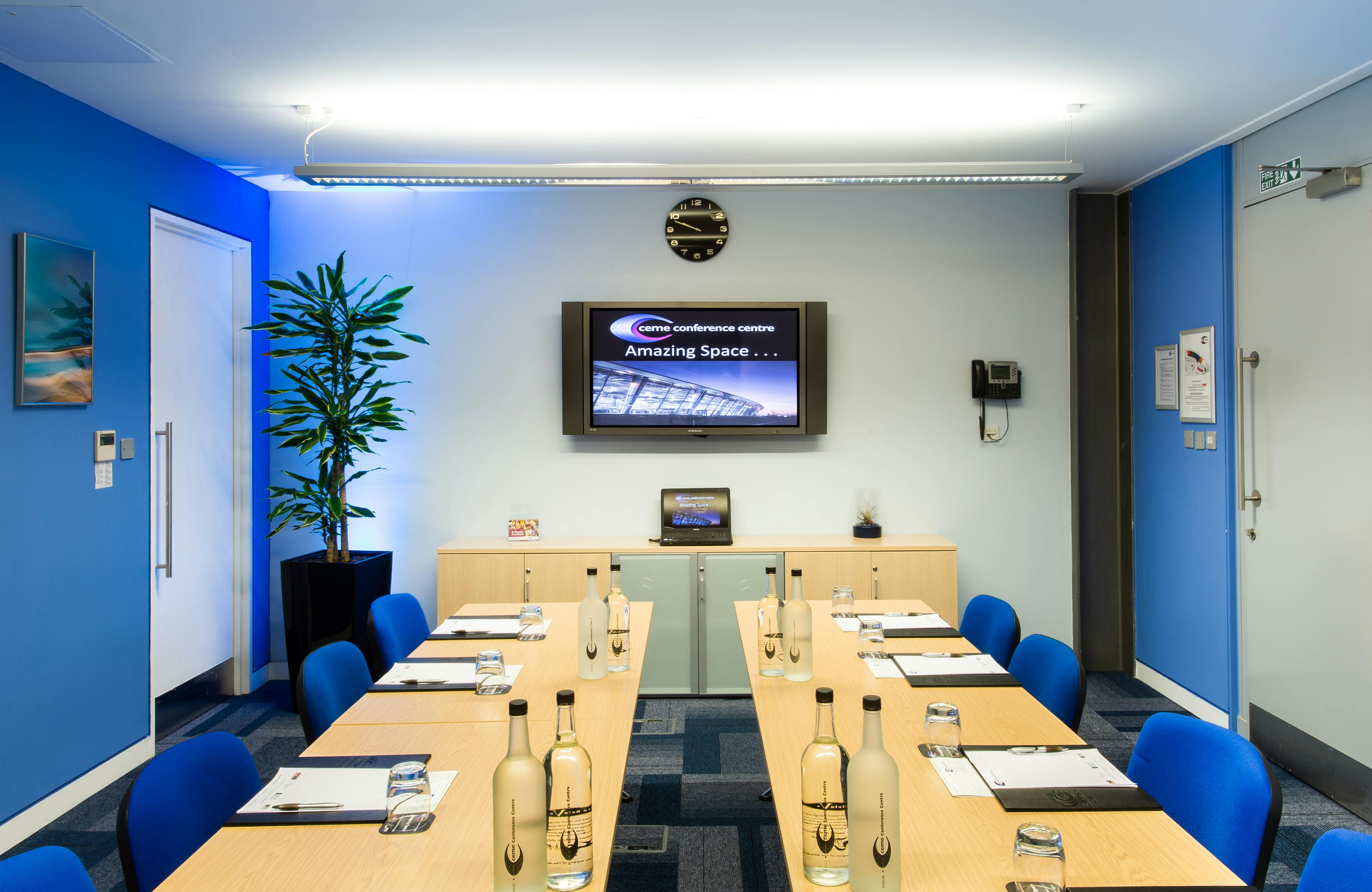 Medium Meeting Room with long table and blue chairs for professional events and presentations.