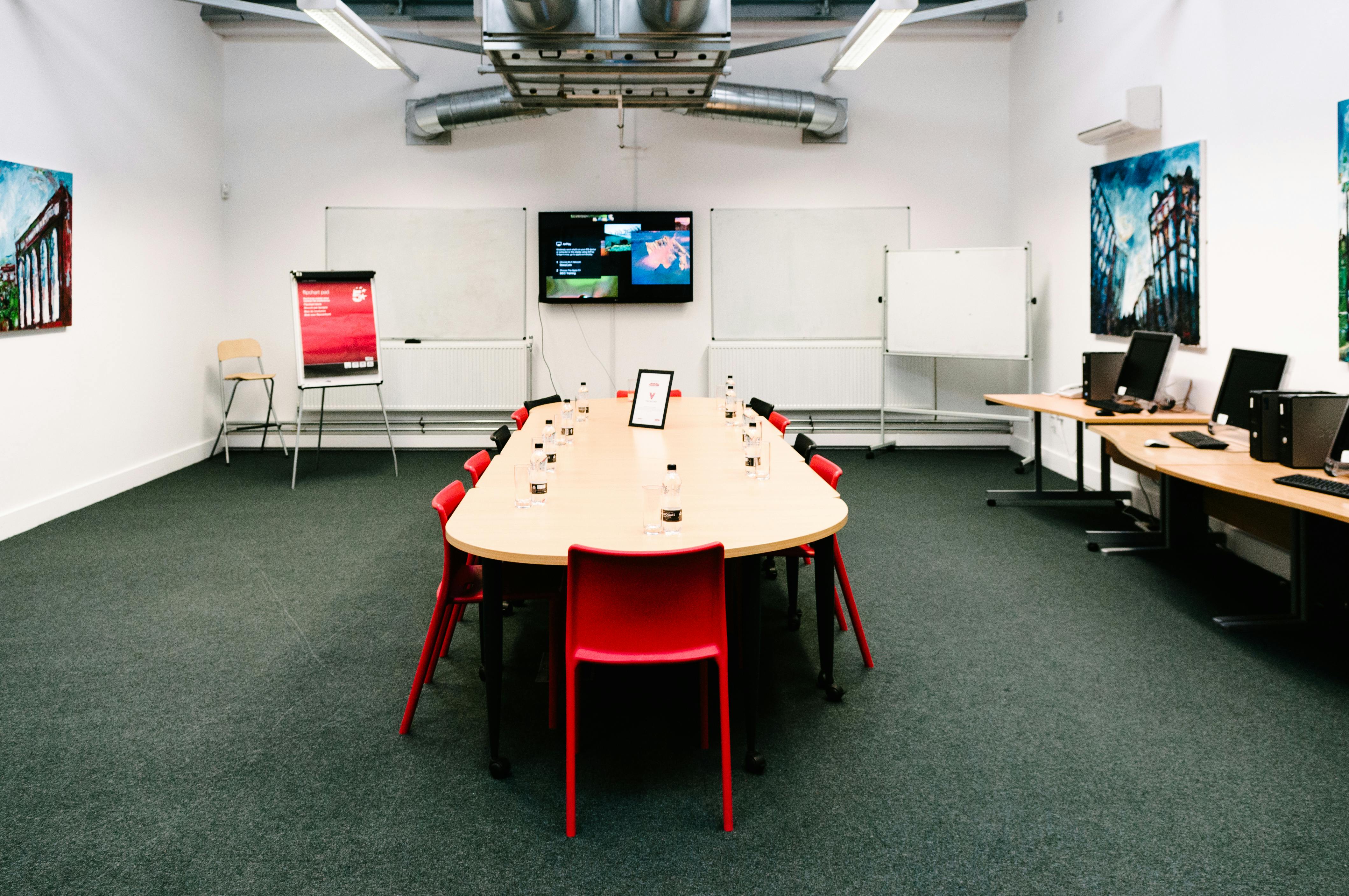 Meeting room with oval table and red chairs, ideal for collaboration and presentations.