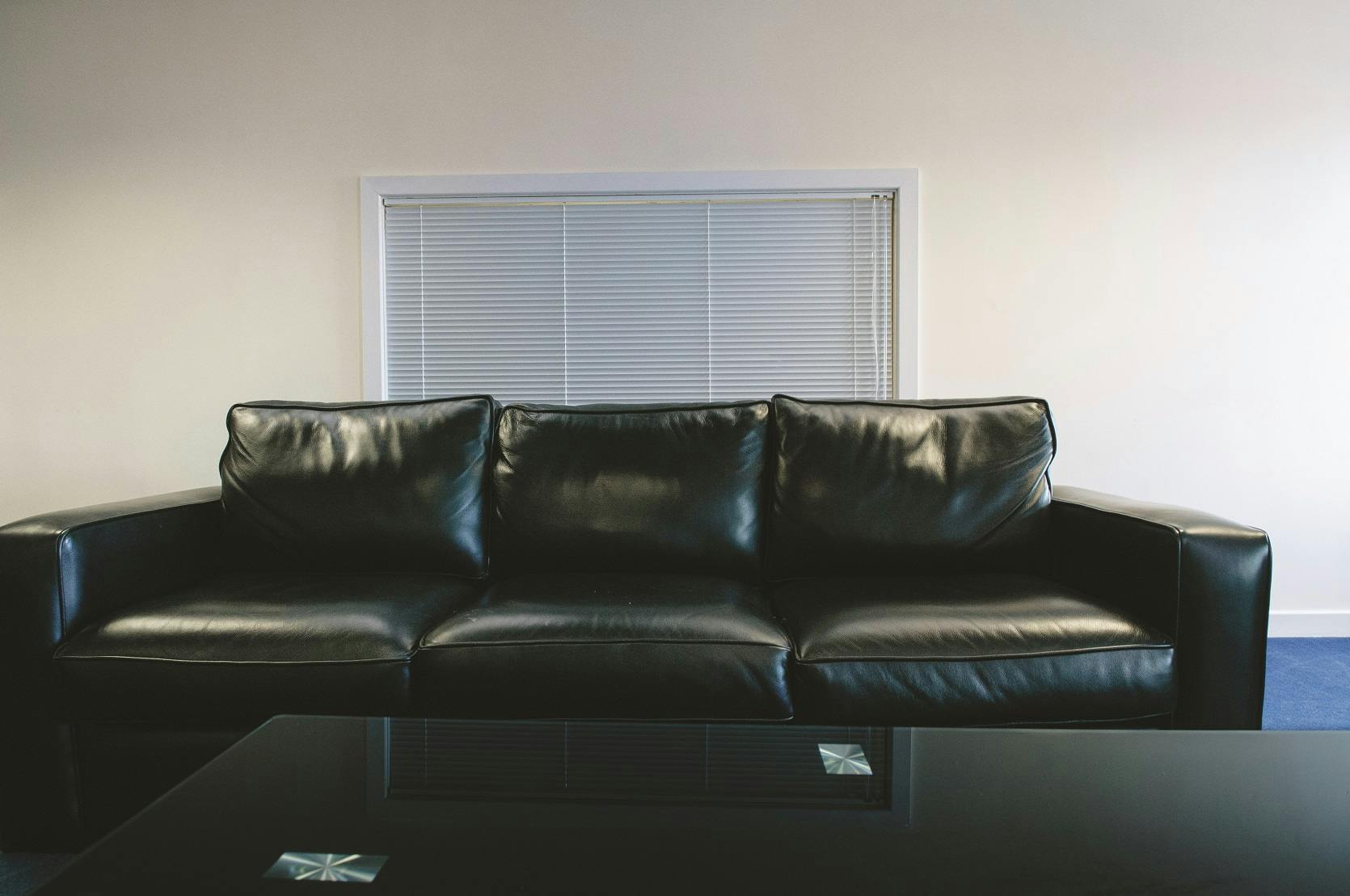 Small Meeting Room with black leather couch, ideal for informal meetings and brainstorming.