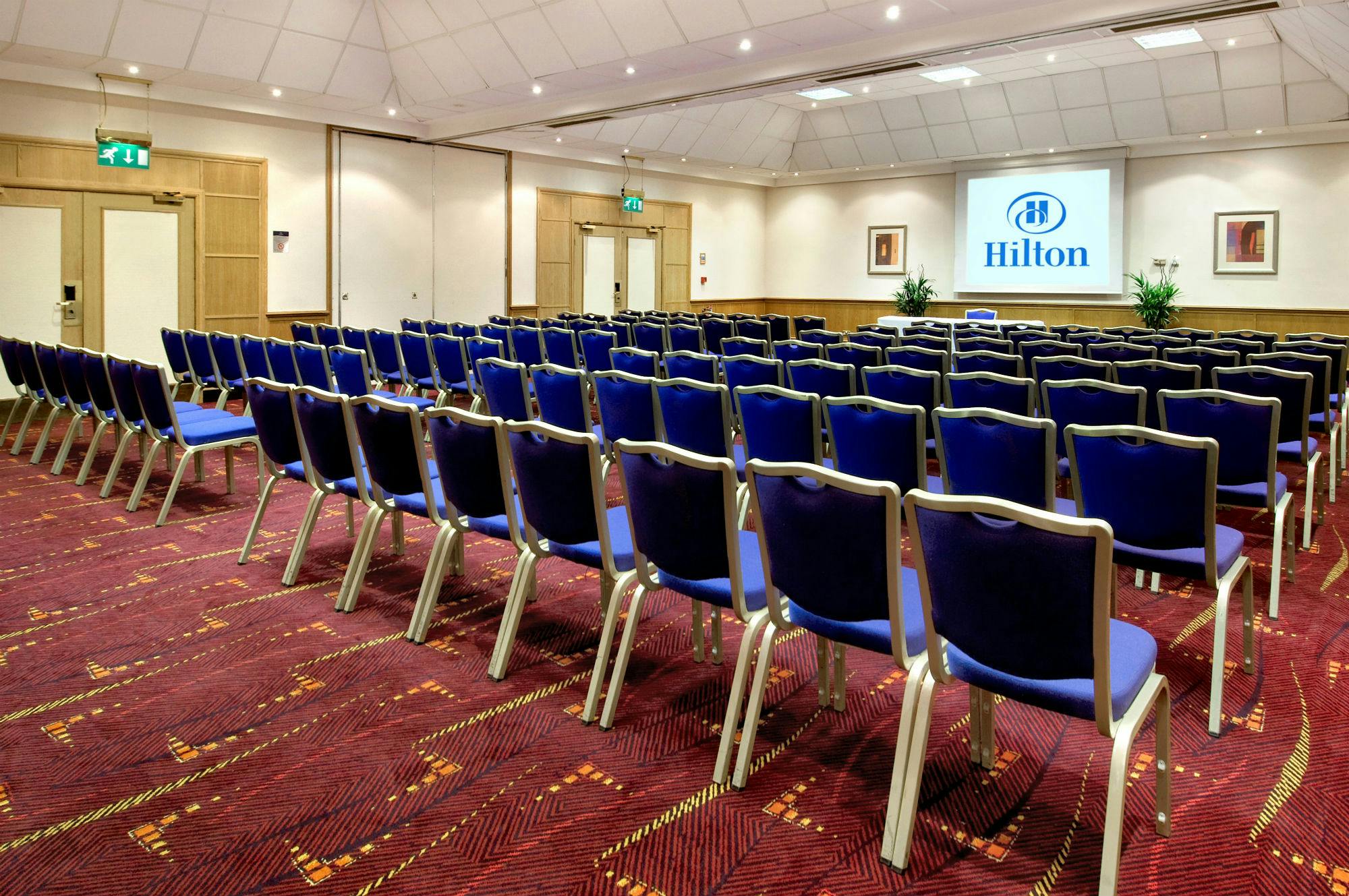 JFK Suite at Hilton Manchester Airport, blue chairs arranged for a professional conference.