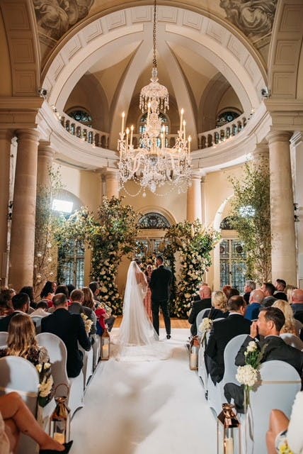 Elegant wedding ceremony in Main Reception Room, adorned with floral decorations and greenery.