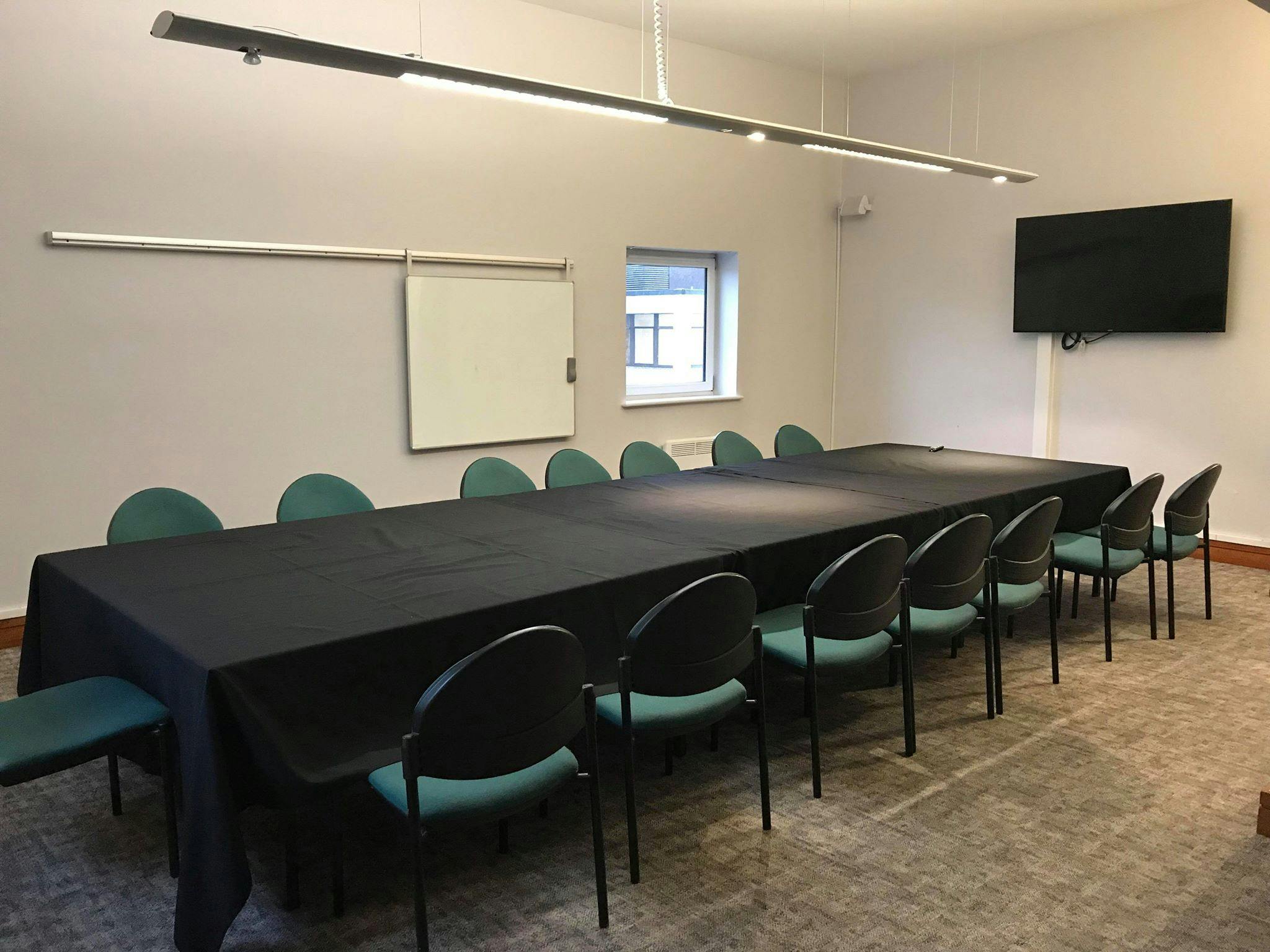 Adamson Suite meeting room with black table and teal chairs, perfect for conferences.