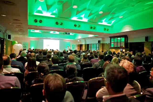 Conference at The Queen Charlotte with green lighting and theater seating for networking.
