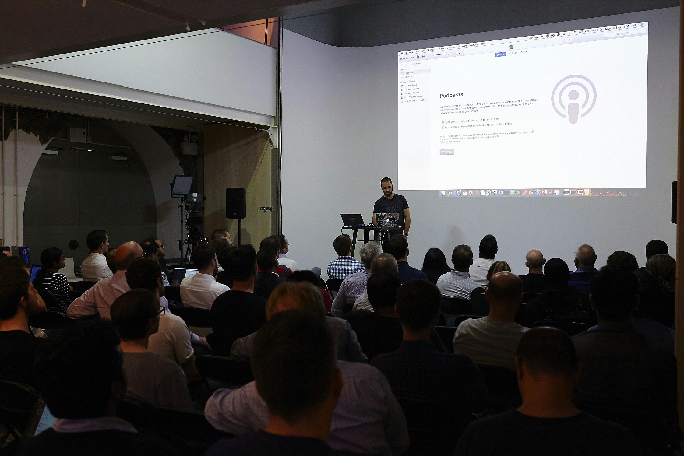 Speaker presenting to engaged audience in modern event space for networking and learning.