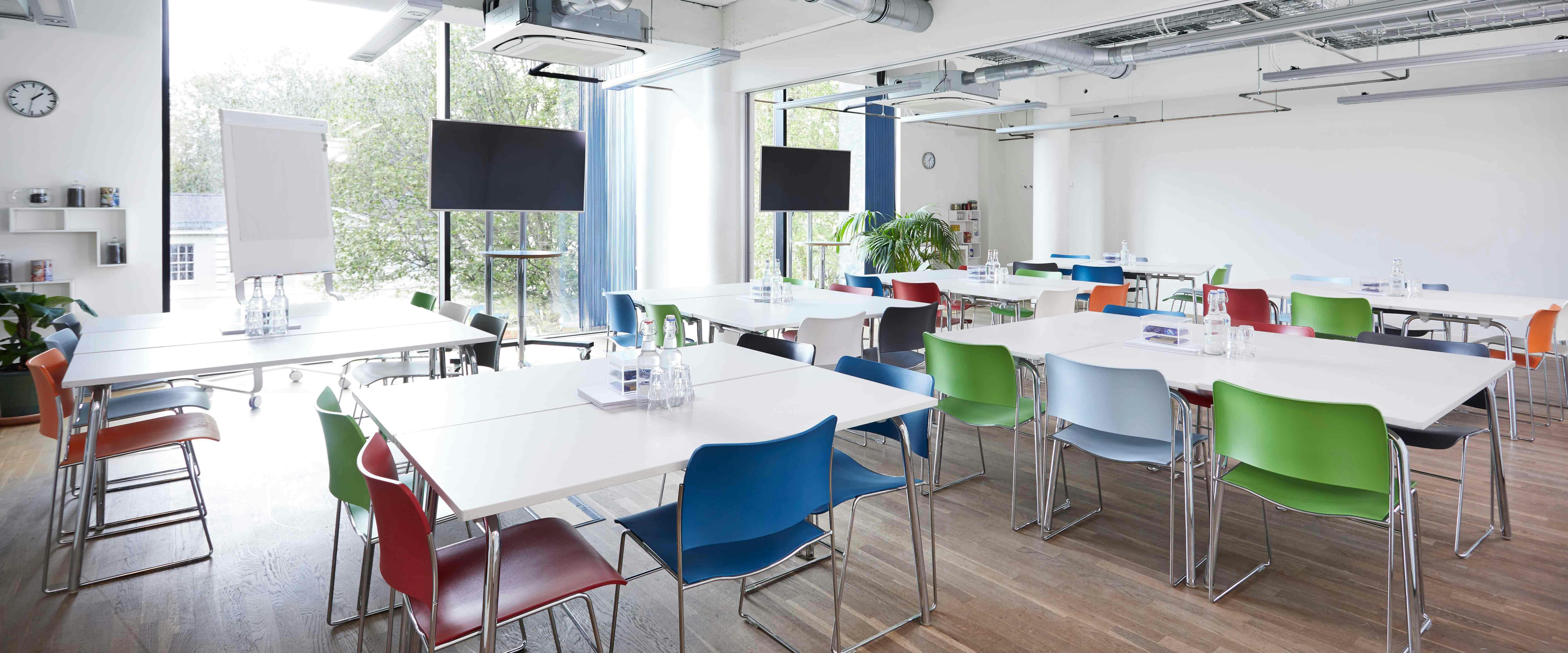 Modern meeting space with colorful chairs, ideal for workshops and brainstorming sessions.