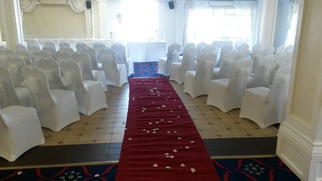 Elegant wedding event space in The Yacht Club with white chairs and red carpet.