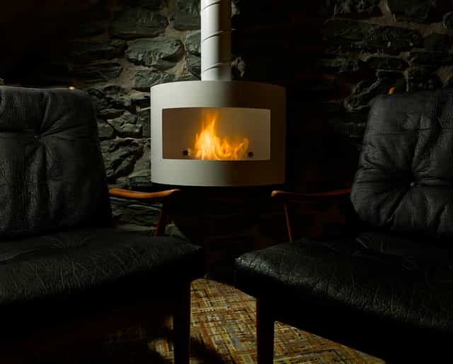 Cozy venue with black leather chairs and fireplace, ideal for meetings and brainstorming.