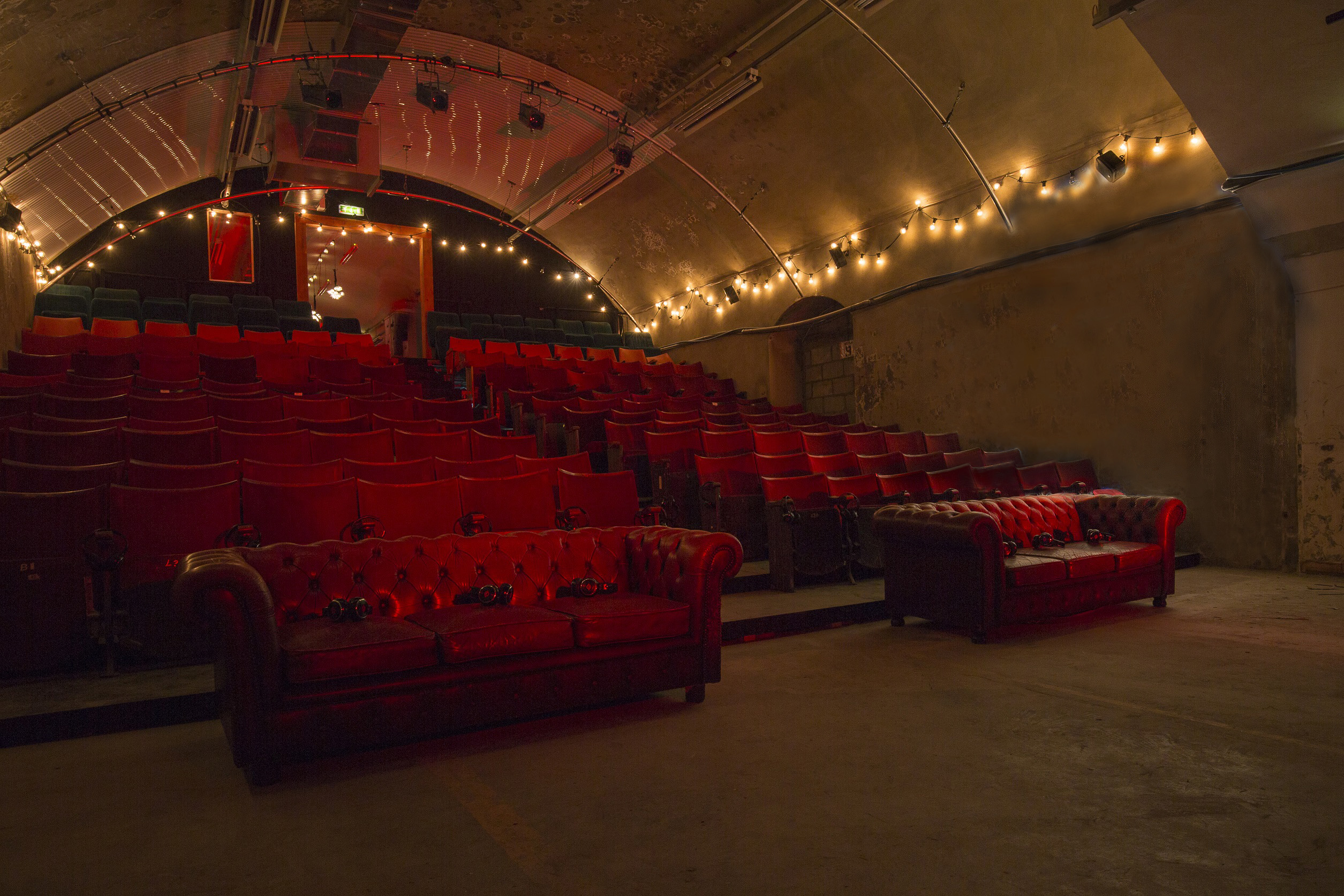Intimate vintage event space with red seating at The Vaults Theatre for gatherings and presentations.
