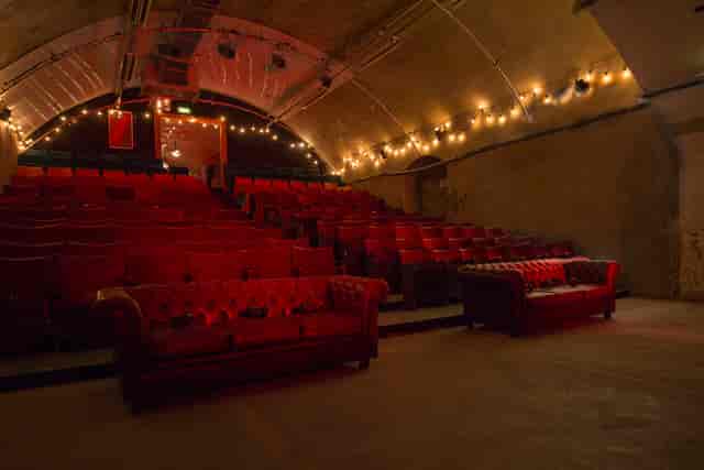 Intimate vintage event space with red seating at The Vaults Theatre for gatherings and presentations.